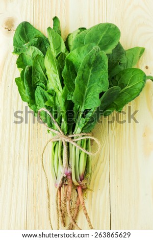 Fresh harvested spinach on a light wooden table, selective focus