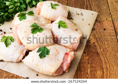 Raw chicken thighs with parsley on wooden table