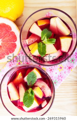 Two glasses of red sangria with limes oranges, apples and grapefruits, top view