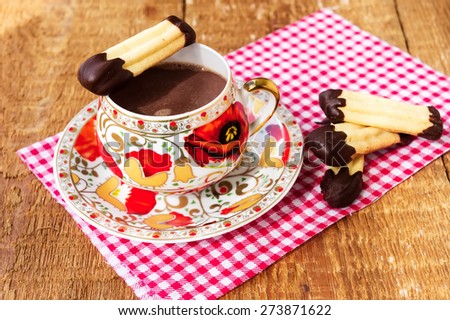 Homemade cookies (finger biscuits with glazed tops) with cup of hot chocolate on rustic wooden table