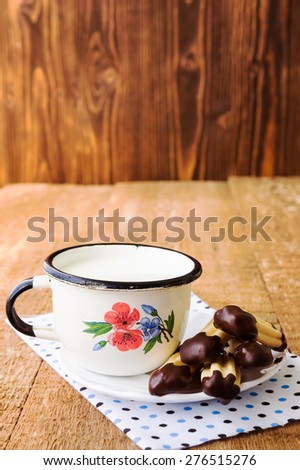 Homemade churros (finger biscuits with glazed tops) with mug of milk on rustic wooden table
