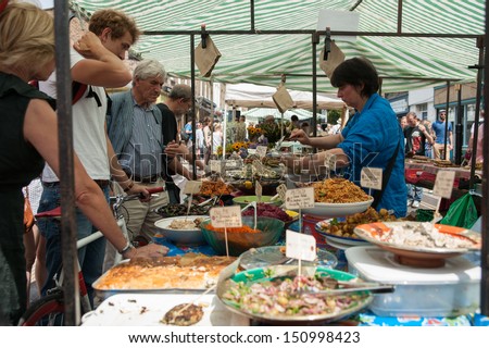 LONDON, ENGLAND - JULY 14: People deciding what to buy from a market stall of prepared food at the Columbia Road Flower Market in Lindon, UK on July 14, 2013.