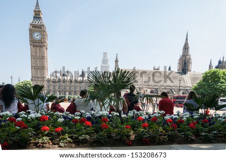 LONDON, ENGLAND - JULY 18: Big Ben and Westminster Palace across the gardens and tourists on July 19, 2013. Tourists gather here to take photos with Big Ben in background.