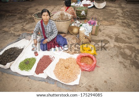 YWAR MA, MYANMAR - NOVEMBER 3; Asian markets, woman sits behind her range of seeds and spices spread on ground sheets and sacks at a traditional market on November 3, 2013 at Ywar Ma Village, Myanmar