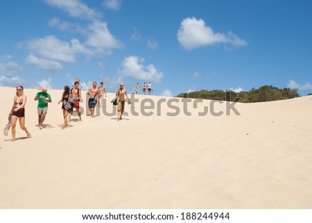 FRASER ISLAND, AUSTRALIA - MARCH 13 - Tourists walk across the desert like sand blow at Lake Wabby, Fraser Island on March 13, 2014 in Fraser Island Australia.