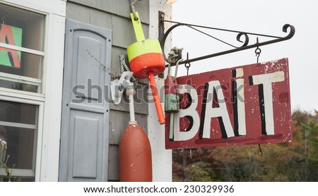 Bait shop sign hang from wall with fishing buoys.