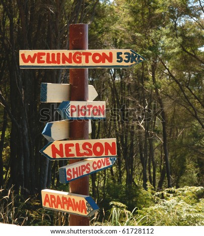 Sign post on bush track giving directions to New Zealand towns and cities.
