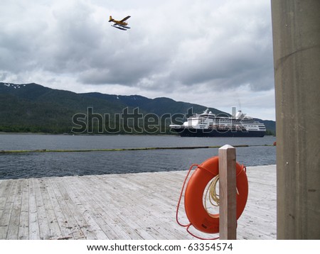 Float plane flys above incoming cruise ship with Ketchican pier and lifesaver in foreground.