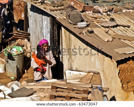 JOHANNESBURG, SOUTH AFRICA - AUGUST 15: Unidentified woman and child in squatter camp on August 15, 2007, in Soweto, Johannesburg, South Africa. Woman holds small child in arms amidst the camp shacks.