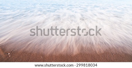Nature abstract water on beach in motion washes like mist over sand leaving patterns