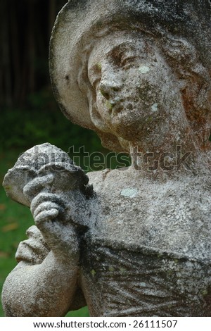 An old weathered statue of a lady holding a flower