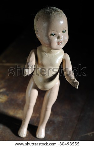 Creepy antique doll standing on distressed wooden background