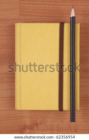 yellow book with pencil on wood background