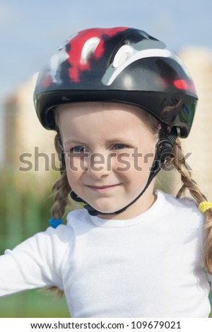 positive portrait of young little skater girl outside in protective helmet