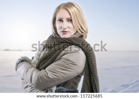 seriously looking blond woman in warm clothing against winter background with using a cooling photo filter