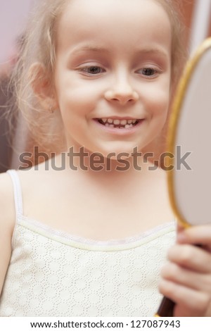 little girl looking in mirror and smiling. shot indoors