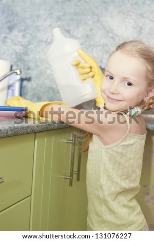 little blond girl makes dishes cleaning using water and sponge shot in household environment