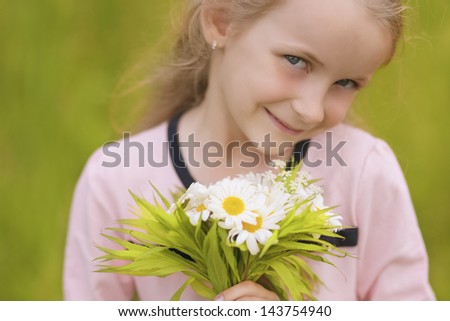 closeup portrait of little caucasian girl with flowers bouquet standing outside