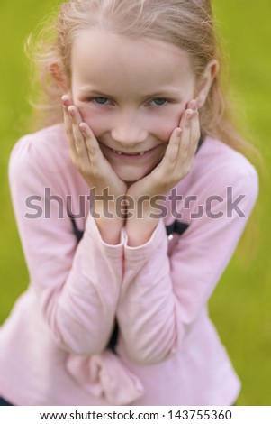 lovely portrait of cute little blond girl showing   positive emotions outside. vertical shot