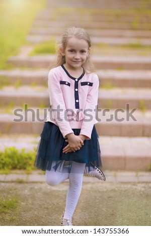portrait of young little girl on stairs smiling and having one leg lifted. vertical shot