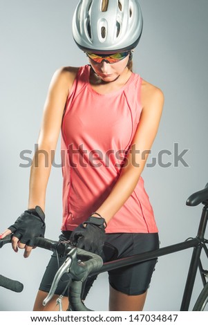 young female sportswoman with old school singlespeed race bike.biker equipped with professional gear, isolated on gray. vertical shot