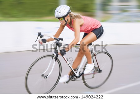 young caucasian female woman riding on the race bike outdoors. panning technique used. horizontal shot