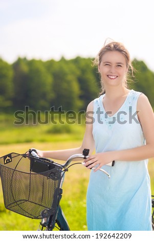 Portrait of Young Happy Caucasian Blond With Bicycle in the Park on a Sunny Day. Vertical Image