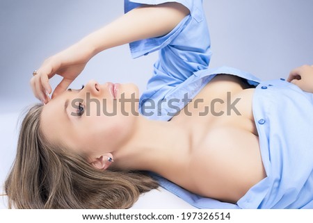 Sensual Dreaming Young Blond Woman Posing in Blue Shirt Lying on Flat Surface. Horizontal Image Composition