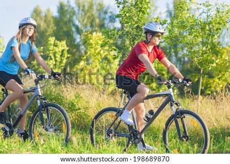 Two Cycling Athletes In Professional Gear Training Outdoor Together in Sunny Day. Horizontal Image