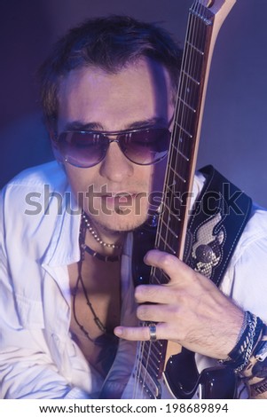 Closeup Portrait of Male Guitar Player Relaxing with Guitar. Vertical Image. Shot Using Long Exposure and Flash Light