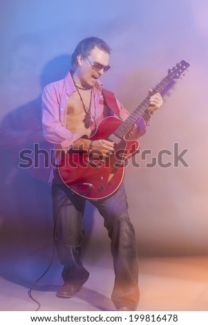 Male Guitarist Playing the Electric Guitar. Shot with Strobes and Halogen Light to Create Mood and Atmosphere. Mixture of Flash and Halogen Lights. Vertical Image