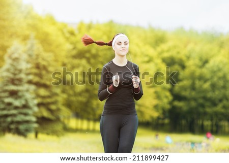 Jogging and Fitness Concepts: Portrait of Beautiful Caucasian Young Woman Jogging  and Listening to Music Outdoors. Horizontal  Image Composition