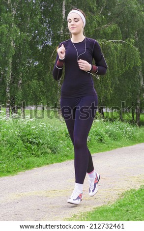 Jogging and Fitness Concepts: Portrait of Beautiful Caucasian Young Woman Jogging  and Listening to Music Outdoors. Vertical Image Composition