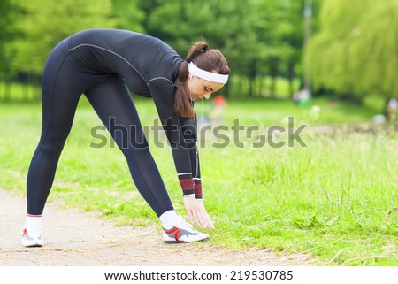 Fitness Concept: Caucasian Woman Stretching Body During Outdoor Workout In the Summer City Park. Horizontal Image