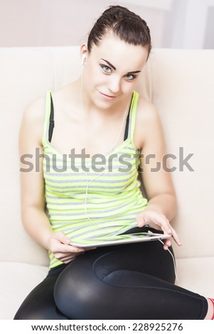 Caucasian Female Using Personal Digital Tablet at Home on Coach. Vertical Image Composition