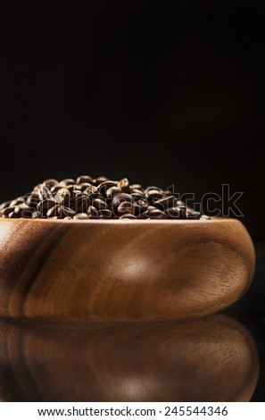 Brown Wooden Bowl Filled with Coffee Beans. Isolated Over Black Background. Vertical Image