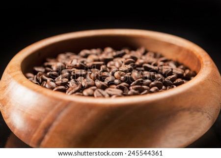 Closeup of Wooden Bowl Filled with Brown Coffee Beans. Over Black Background. Horizontal Image