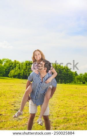 Smiling Caucasian Man Giving Woman Piggyback Ride Outdoors. Youth Lifestyle, Happiness, Love, dating, Romance , Vacation Concept. Vertical Image Shot