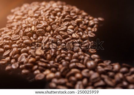 closeup of Line made of Roasted Coffee Beans Over Black Background. Light Effect Used. Horizontal Image