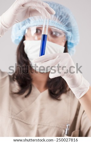 Closeup of Female Laboratory Staff Hands Looking at Test Tube With Liquid and Analyzing.Against Gray Background. Vertical Image Composition