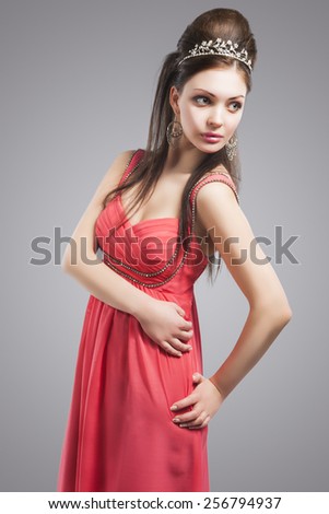 Portrait of Sensual Relaxing Caucasian Woman In Oink Evening Dress. Woman Wearing Silver Queen Crown. Against Grey Background