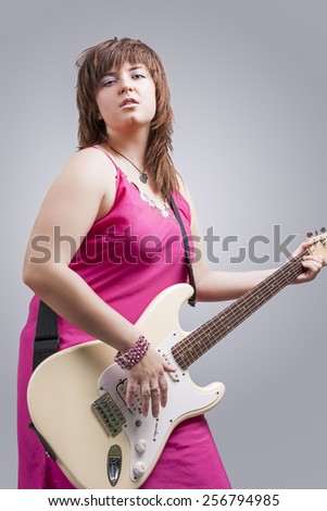 Sexy Brunette Lady Playing the Guitar with Expression. Against Gray Background. Vertical Image Composition