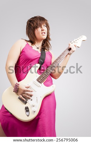Young and Sexy Brunette Girl With Guitar Playing Expressively. Against Gray Background. Vertical Image Composition
