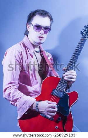 Portrait of Handsome Caucasian Man Posing with His Modern and Stylish Acoustic Guitar. Vertical Composition
