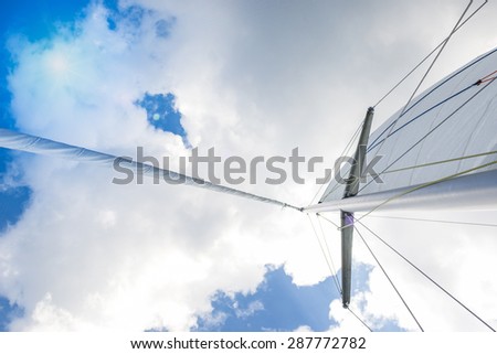 Closeup View of Mid-Size Yacht Mast and Canvas Sail Shot Against Bright Summer Sun. Horizontal Image Orientation