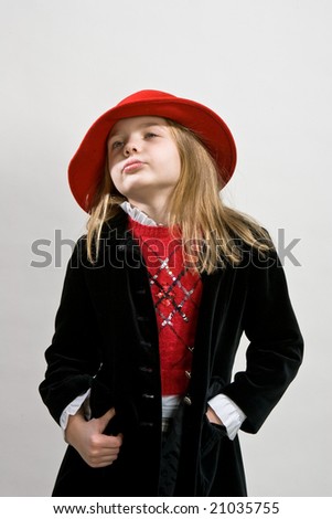 young blonde girl in red jacket red hat  standing turned left