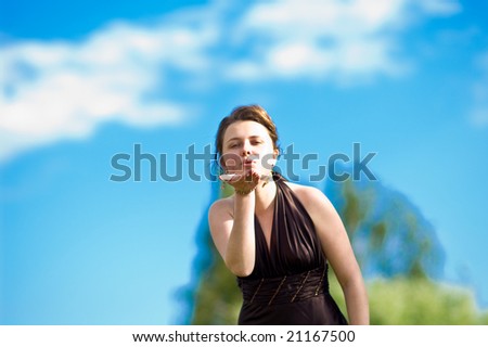 young pretty female with curly set hair sending a kiss standing in sever purple dress