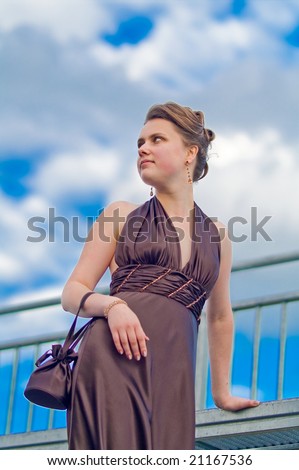 young pretty girl standing on the platform with head turned up and inclined left thinking in free pose relaxing blue skies