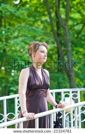 young charming lady with curly fashion hair dressing and silk skin standing on the bridge thinking in sever violet dress
