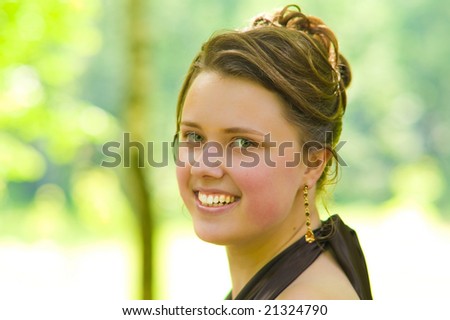 face of young charming lady with curly fashion hair dressing and silk skin standing smiling with brilliant smile looking forward with body turned left in violet dress green background